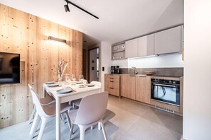 A modern kitchen with wooden cabinetry, a dining table set for four, and a built-in oven. - 350m from ski lifts, 2nd floor, balcony, parking, tv, ski locker, 41m², Morzine (Morzine)