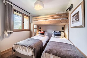 A room with two beds, a window with curtains, a mounted TV, and a framed picture on the wall. - 350m from ski lifts, 2nd floor, balcony, parking, tv, ski locker, 41m², Morzine (Morzine)