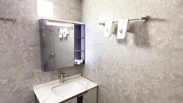 A bathroom with a white sink, a mirror, a towel rack, and a trash bin.