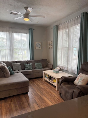 A living room with a sofa, armchair, coffee table, and a ceiling fan. - Three bedroom house in charming Galveston.  Close to beach and restaurants, (Galveston)