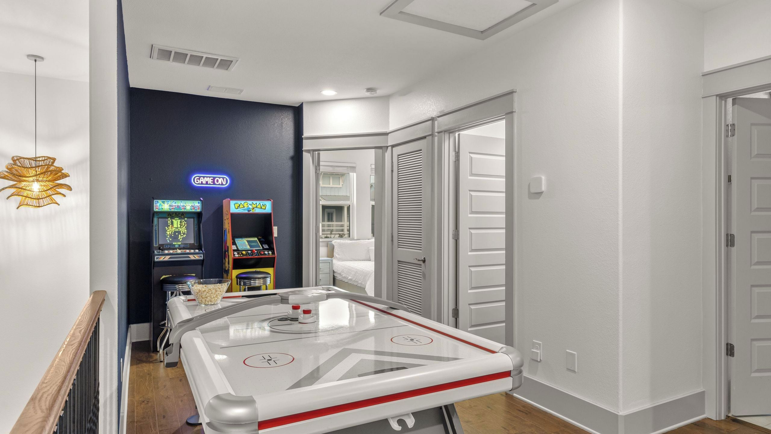 A hotel room with a pool table, arcade games, and a view of the outside.