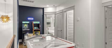 A hotel room with a pool table, arcade games, and a view of the outside.