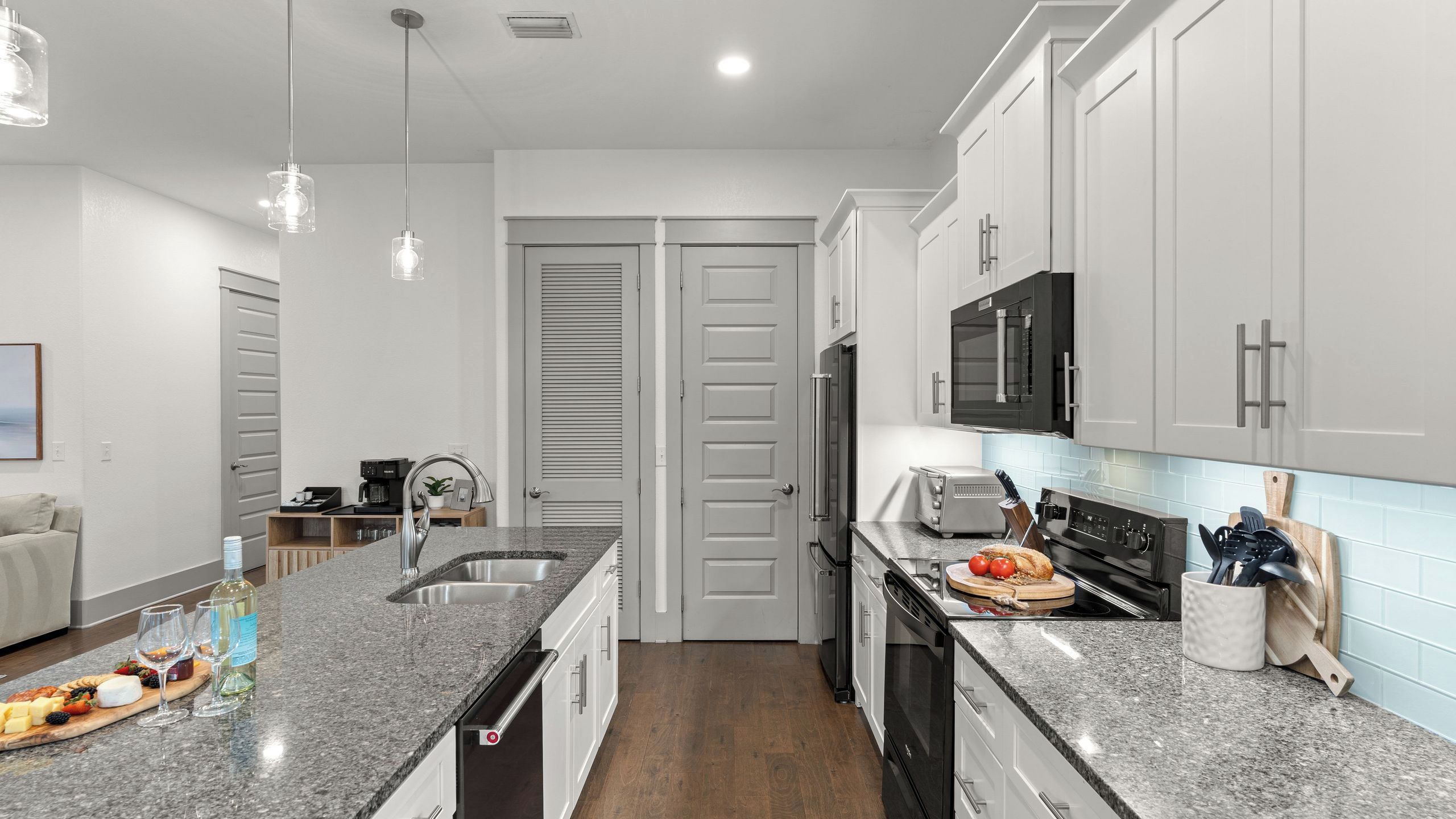 A modern kitchen with granite countertops, stainless steel appliances, and white cabinetry.