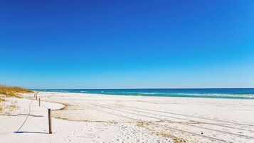 Una playa con cielo despejado, orilla arenosa y una cerca.