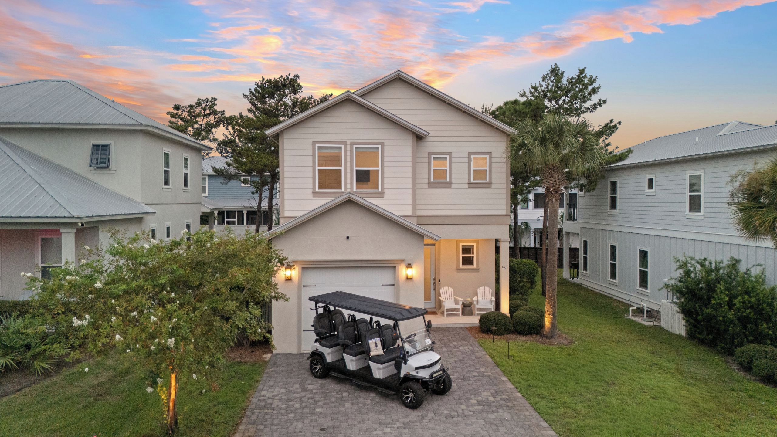 A two-story residential building with a garage, a golf cart, and a well-maintained lawn.