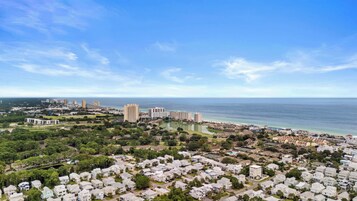 A coastal residential area with a mix of single-family homes and high-rise buildings, a clear sky, and a view of the ocean.