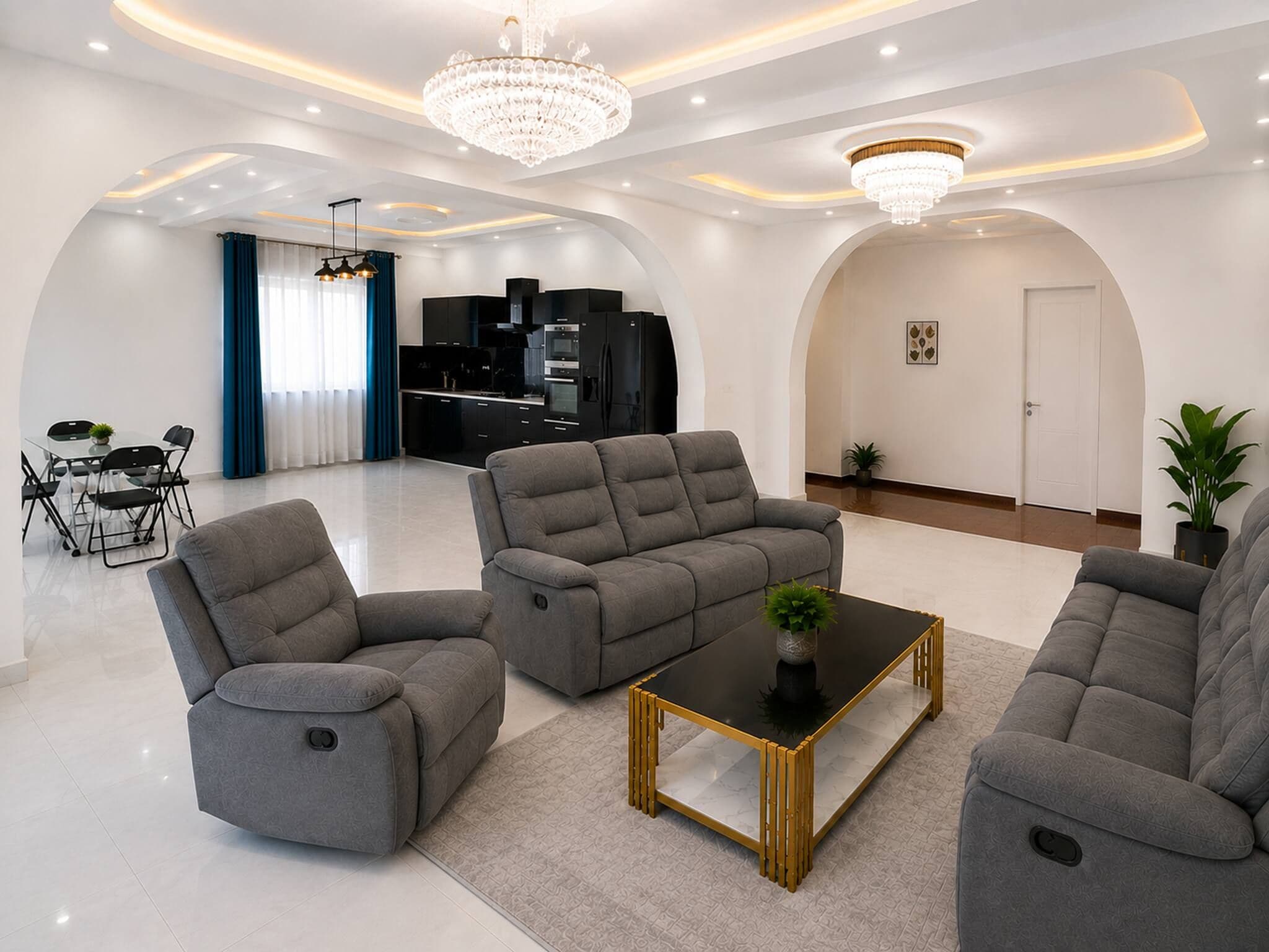 A modern living room with grey sofas, a glass dining table, and a black coffee table.