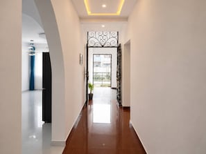 A hallway with a polished floor, a decorative metal gate, and a potted plant.