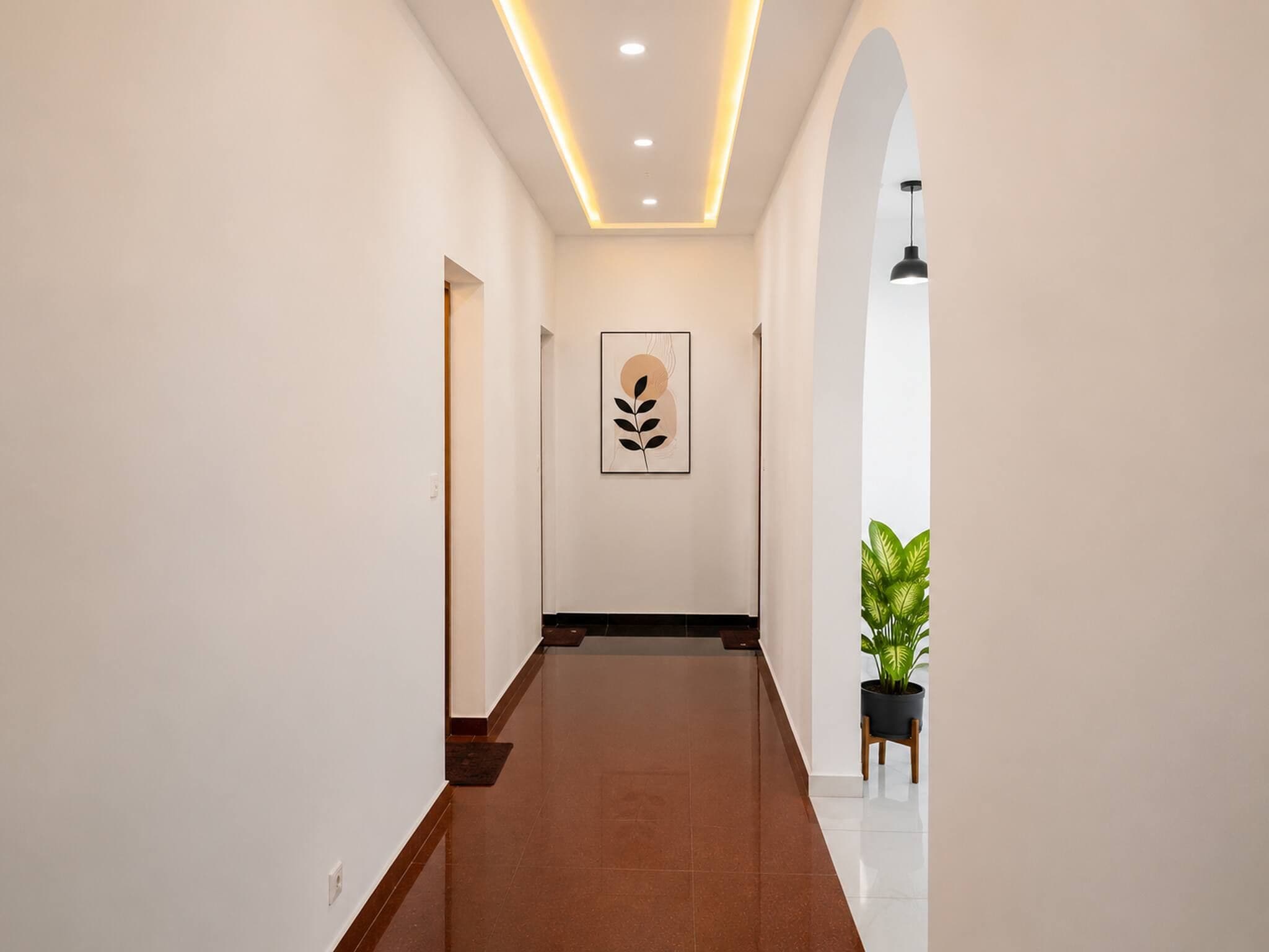 A hallway with a ceiling light, a framed artwork, and a potted plant.