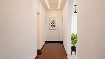 A hallway with a ceiling light, a framed artwork, and a potted plant.