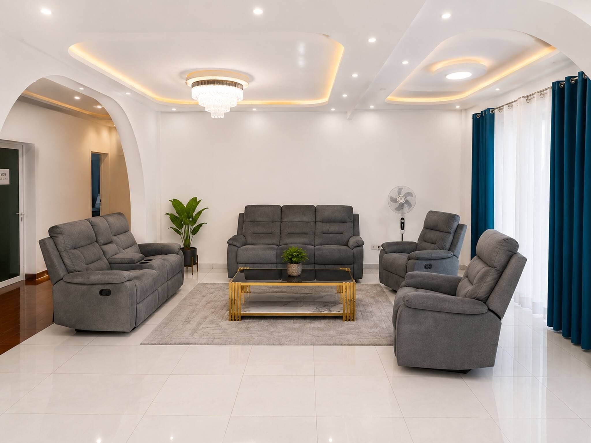 Ein modernes Wohnzimmer mit einer grauen Sofagarnitur, einem Couchtisch und einem Ventilator.