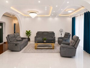 A modern living room with a grey sofa set, a coffee table, and a fan.