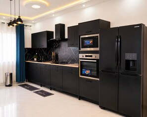 A modern kitchen with black cabinetry, stainless steel appliances, and a digital oven control panel.