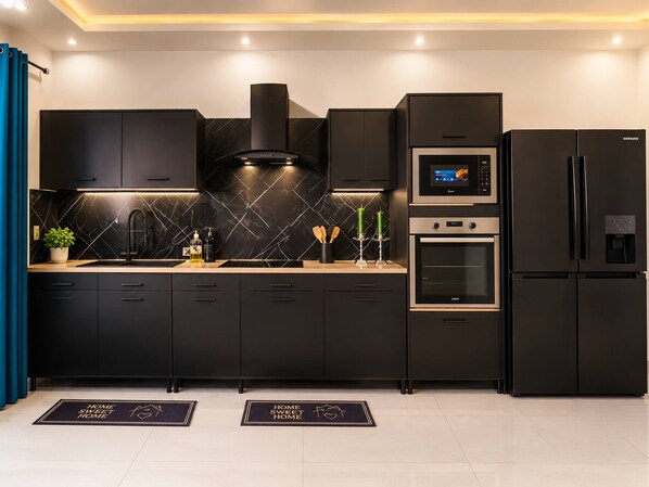 A modern kitchen with black cabinetry, a built-in oven, a microwave, and a Samsung refrigerator.