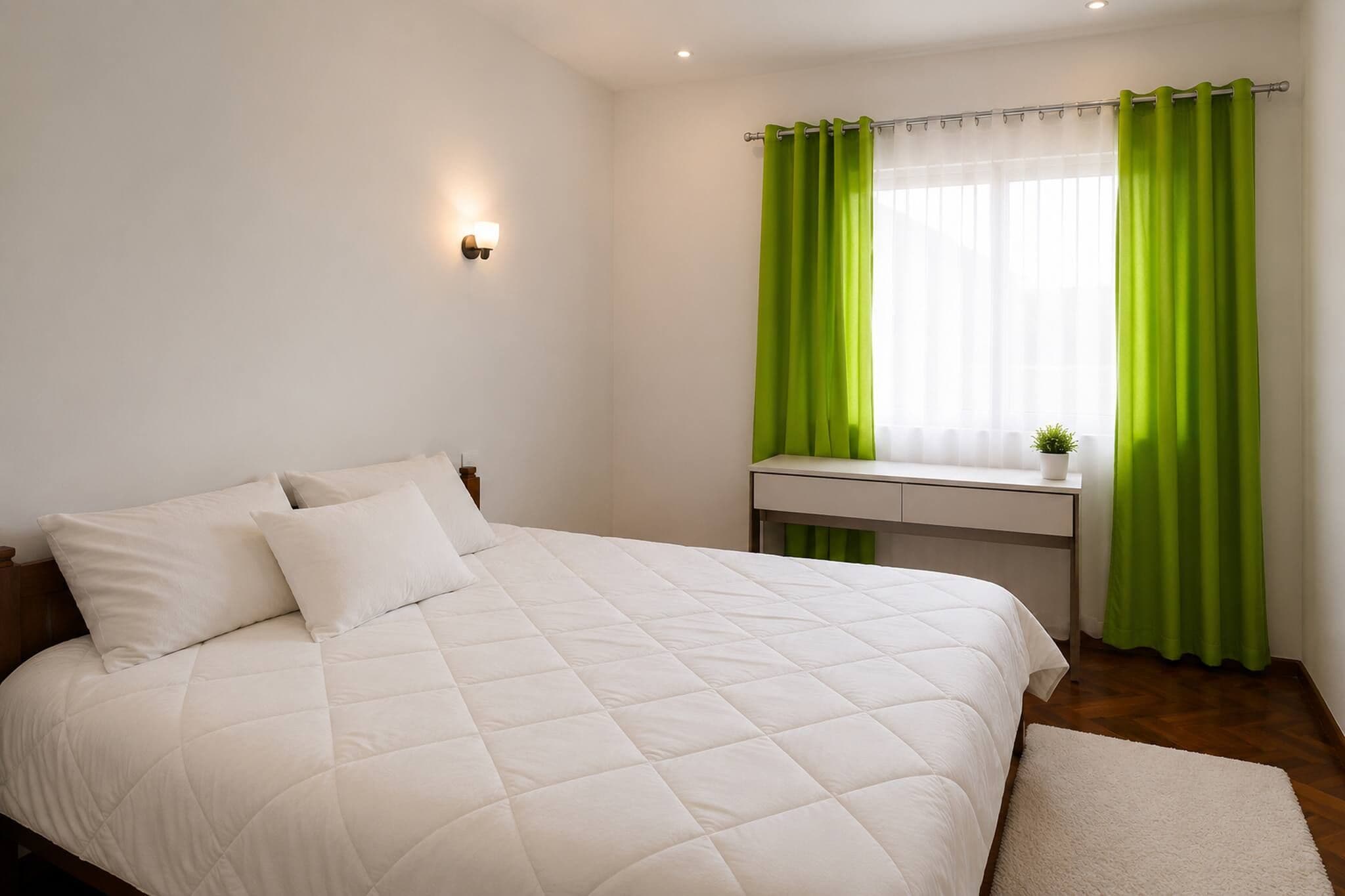 Ein Schlafzimmer mit einem Bett, einem Schreibtisch und einem Fenster mit grünen Vorhängen.