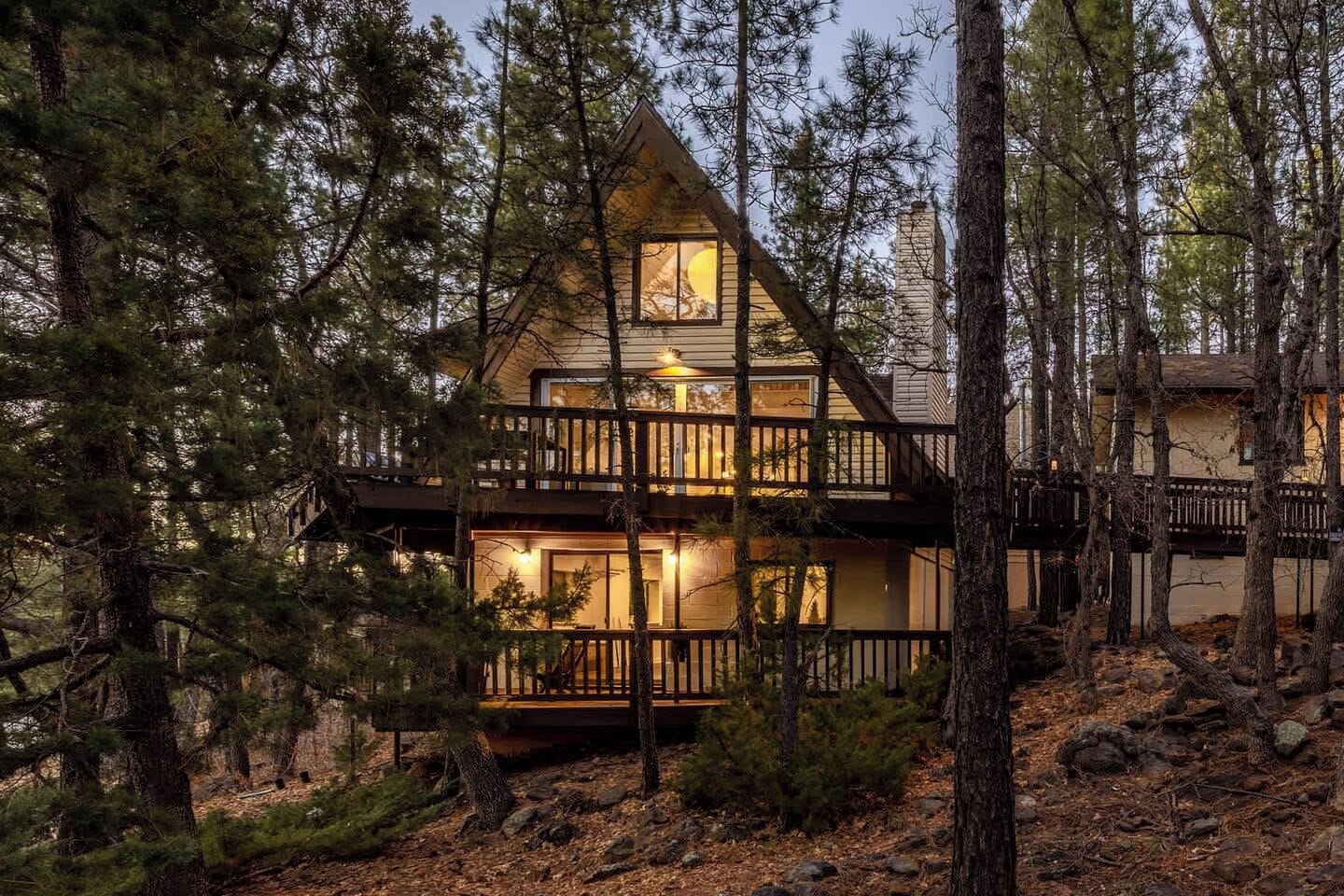 Une cabine avec une façade en bois, plusieurs terrasses et un éclairage intérieur chaleureux.