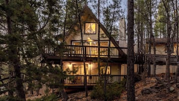 Une cabine avec une façade en bois, plusieurs terrasses et un éclairage intérieur chaleureux.