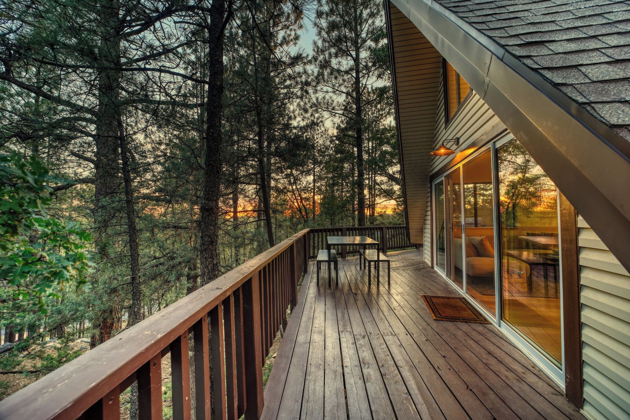 Um deck de madeira com guarda-corpo, com vista para uma área arborizada.