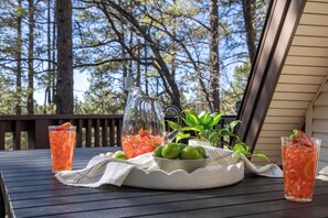 A table set outdoors with drinks, a pitcher, and a bowl of limes.