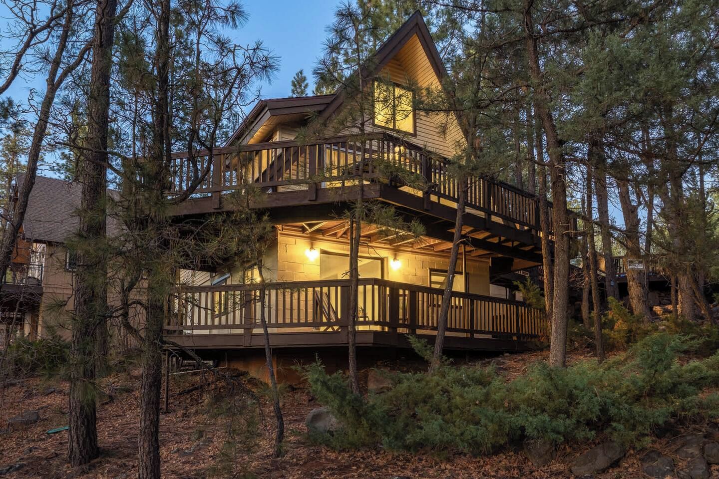 Une cabane en bois à deux étages, dotée d’un balcon et entourée d’arbres.