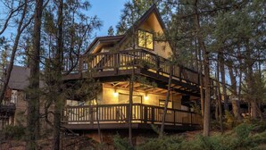 Eine zweistöckige Holzhütte mit Balkon, umgeben von Bäumen.