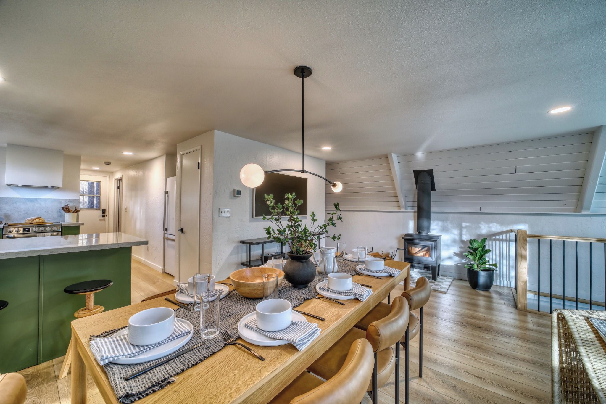 A modern kitchen with a dining area, a built-in stove, and a large window.