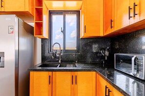 Eine Küche mit Holzschränken, einem Edelstahlkühlschrank, einer Spüle mit Wasserhahn und einer Mikrowelle.