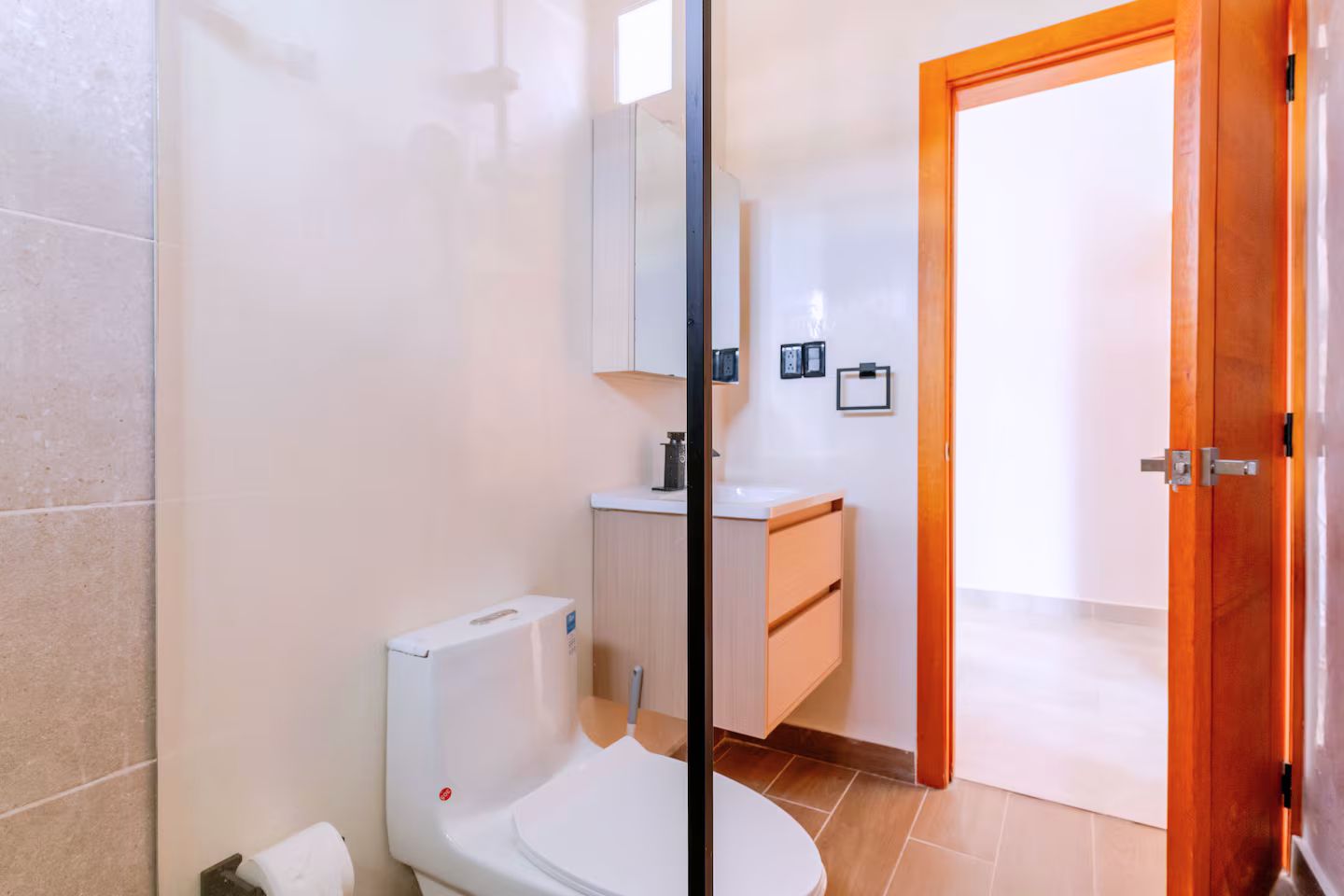 A bathroom with a toilet, a sink, and a mirror.