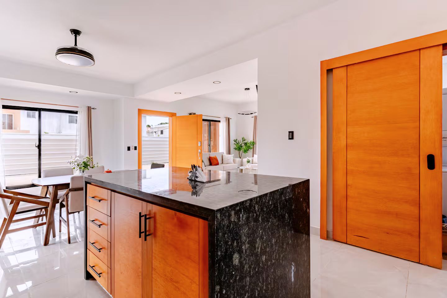 Una cocina moderna con una isla central, armarios de madera y una puerta grande de madera.