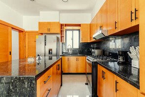 Une cuisine moderne avec des meubles en bois, un plan de travail en granit, des appareils électroménagers en acier inoxydable et une fenêtre qui laisse entrer la lumière naturelle.