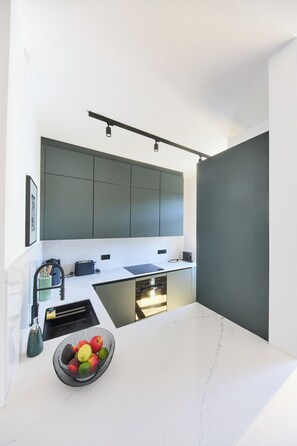 Een moderne keuken met een wit aanrechtblad, donkere kastjes en een ingebouwde oven.