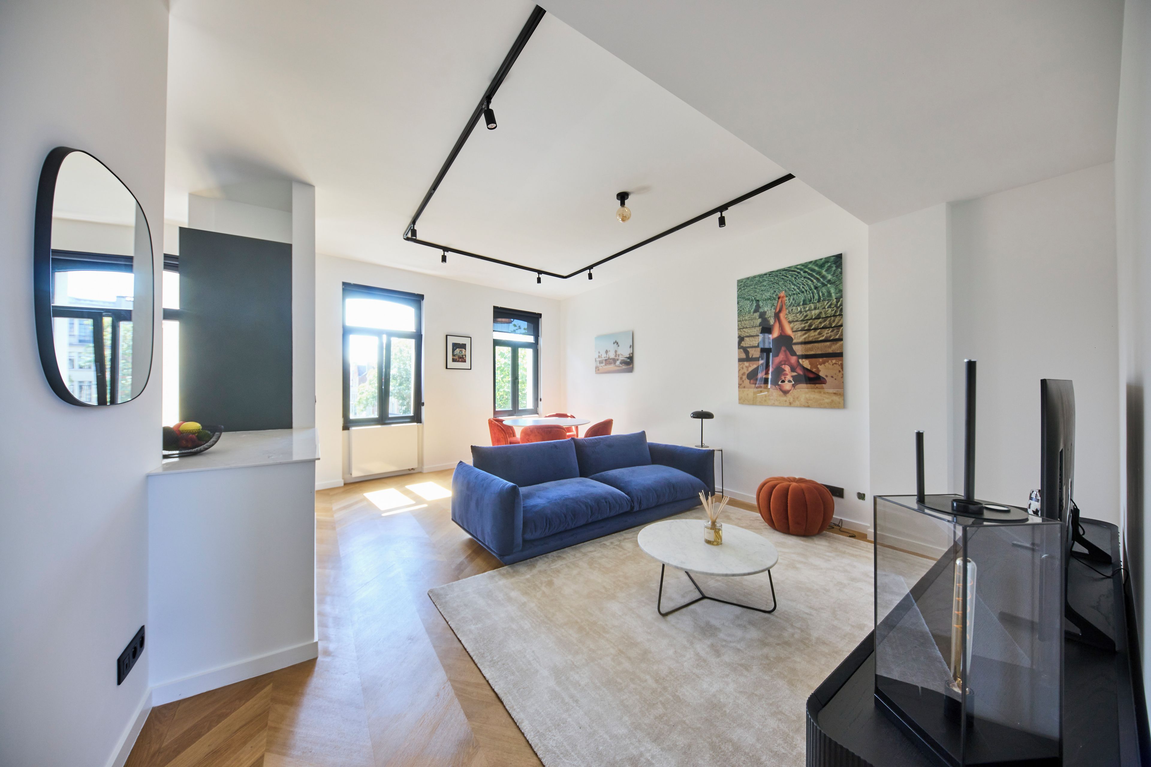 Un salon moderne avec un canapé bleu, une table basse ronde et un téléviseur à écran plat.