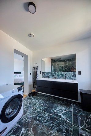 A modern bathroom with a large mirror, a washing machine, and a black cabinet. - Stylish Apartement in The Heart of the City (Ixelles)