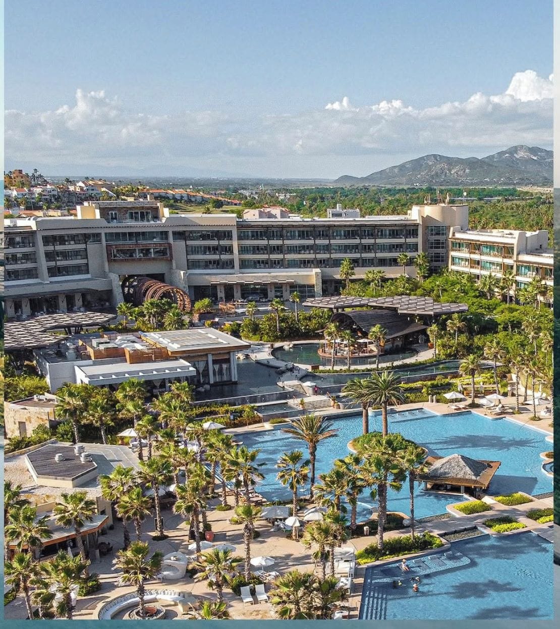 Resort com várias piscinas, palmeiras e um extenso complexo de edifícios.