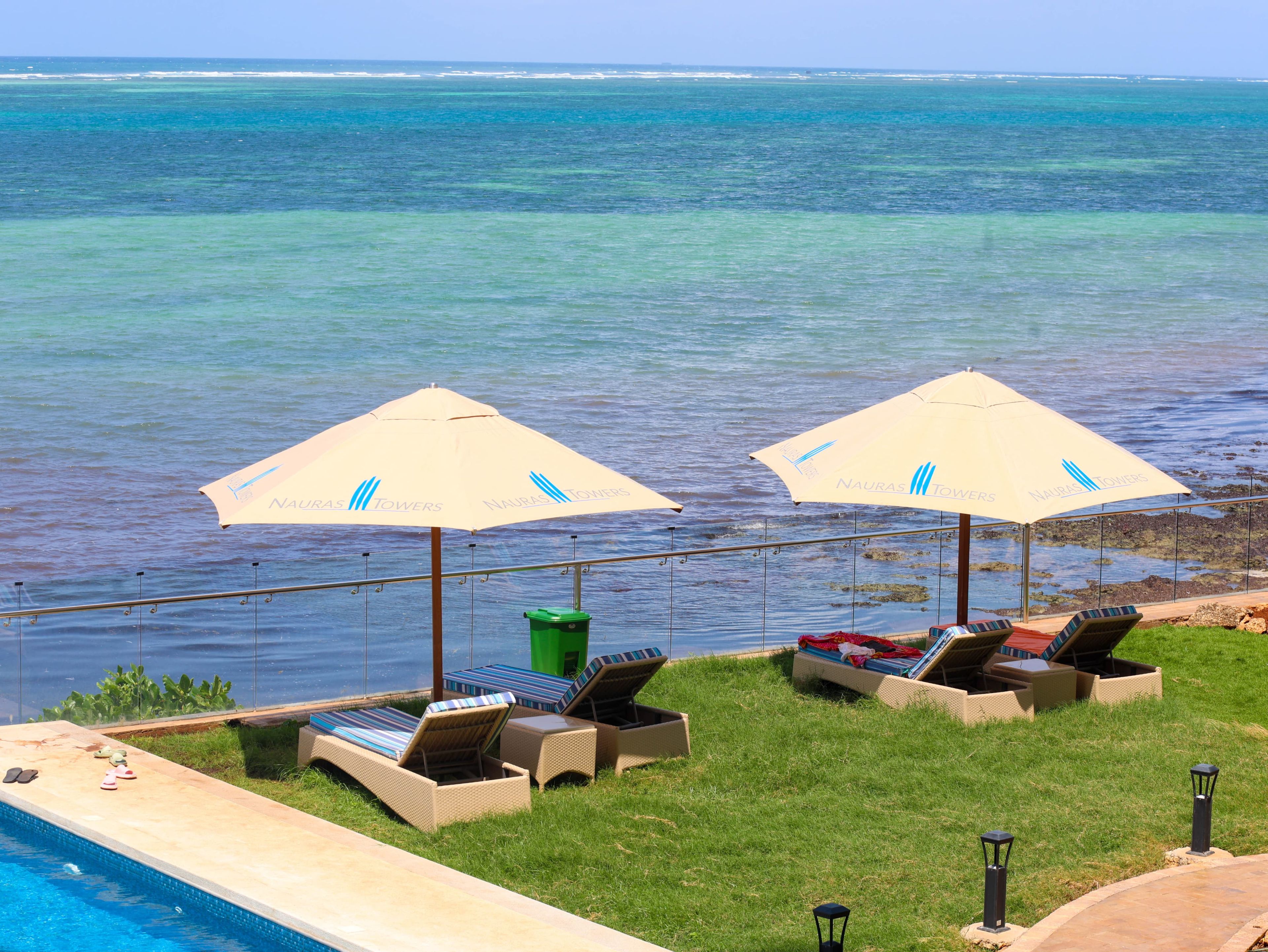 A poolside area with lounge chairs and umbrellas, overlooking a body of water.
