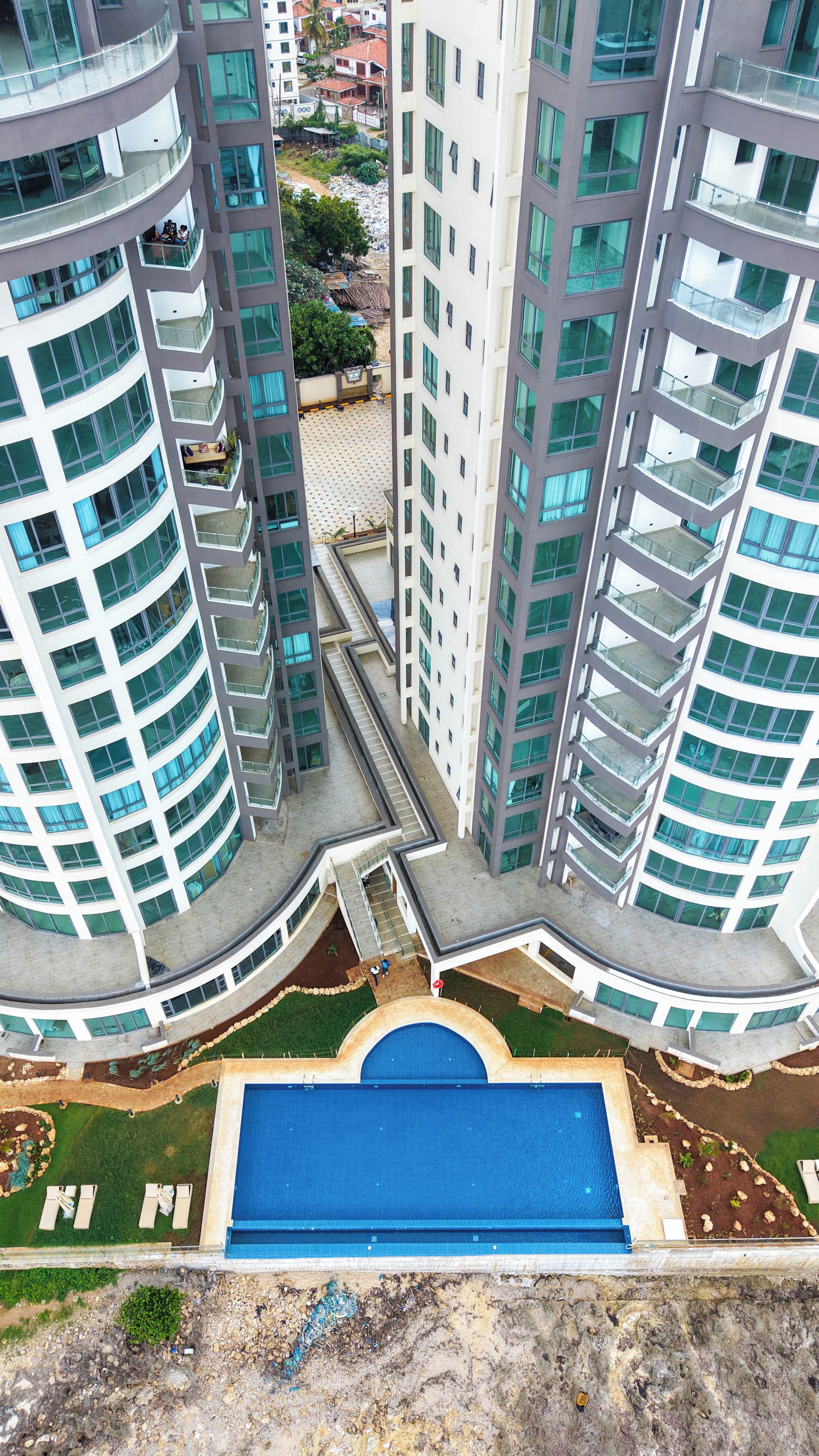 A high-rise building with multiple balconies and a central courtyard with a swimming pool.