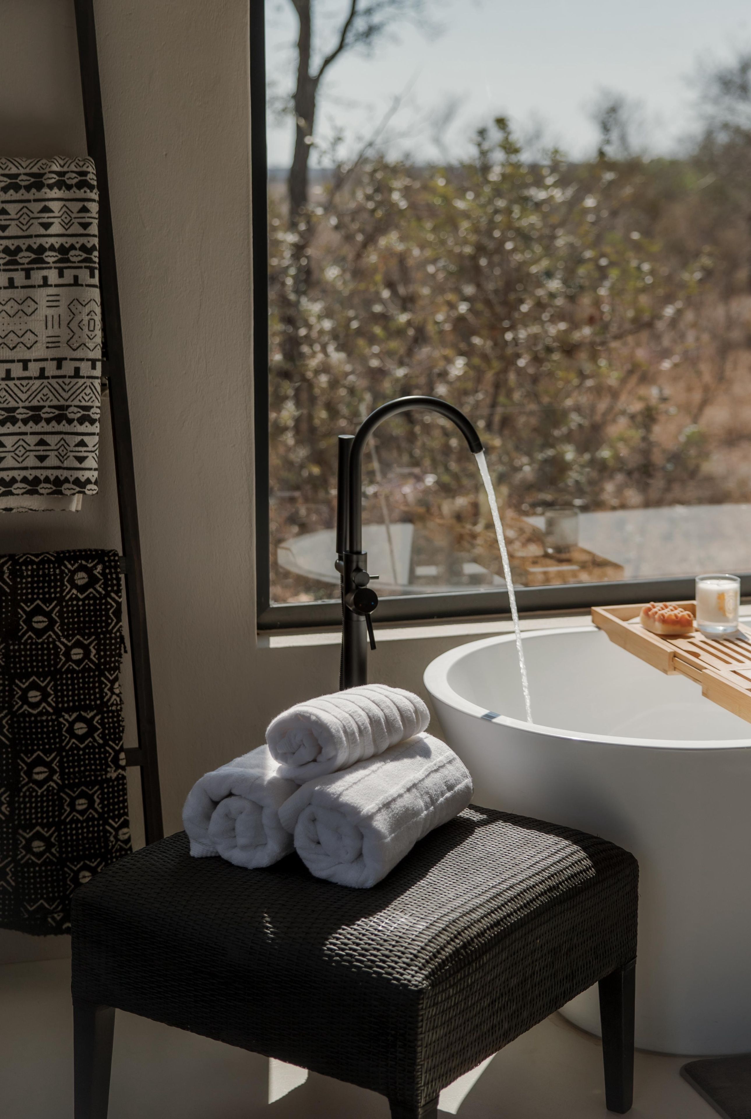 Une salle de bain avec un lavabo rond, un porte-serviettes et une fenêtre donnant sur les arbres.