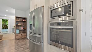 A modern kitchen with stainless steel appliances, including a refrigerator, microwave, and oven. - Hale Pōmaikai by Avantstay Ocean View Lanai + Covered Dining Minutes to Poipu Beach & Koloa (Koloa)