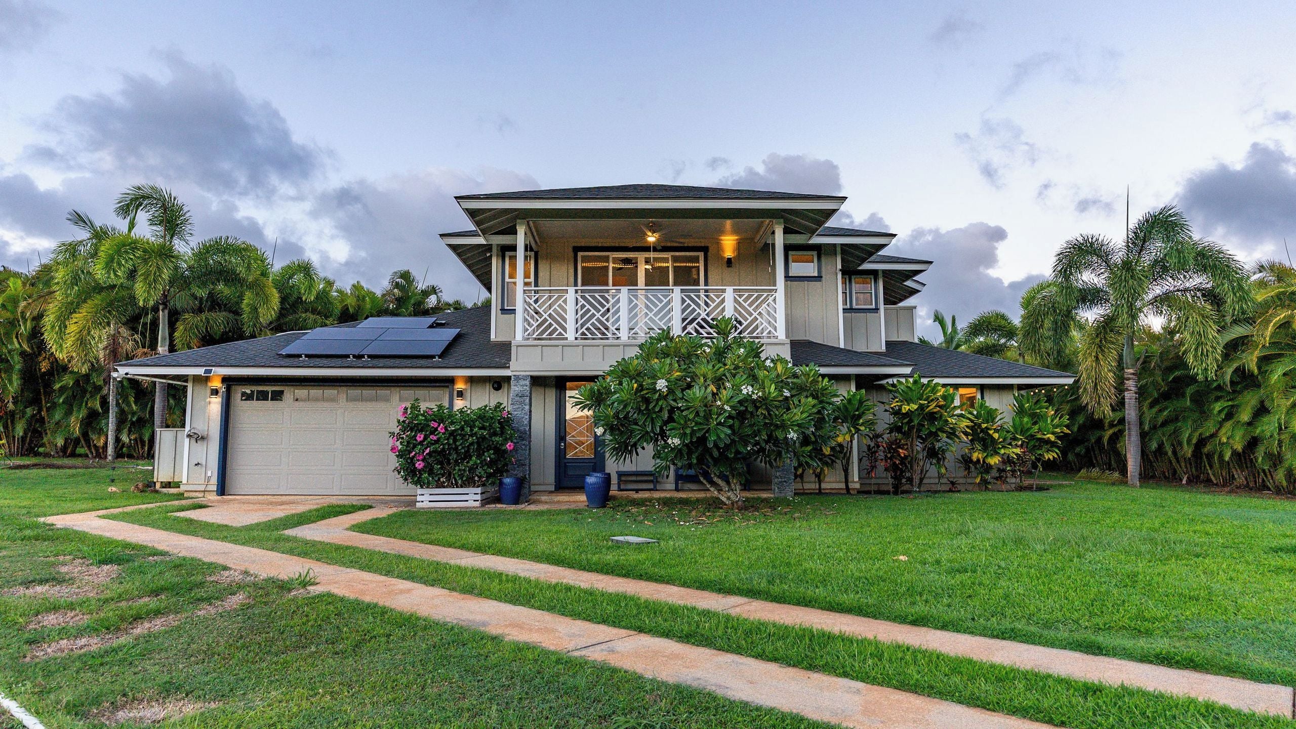 A two-story house with a garage, solar panels, and a well-maintained lawn.