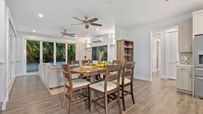 A modern kitchen with wooden cabinetry, a dining area with a round table and chairs, and a ceiling fan. - Hale Pōmaikai by Avantstay Ocean View Lanai + Covered Dining Minutes to Poipu Beach & Koloa (Koloa)