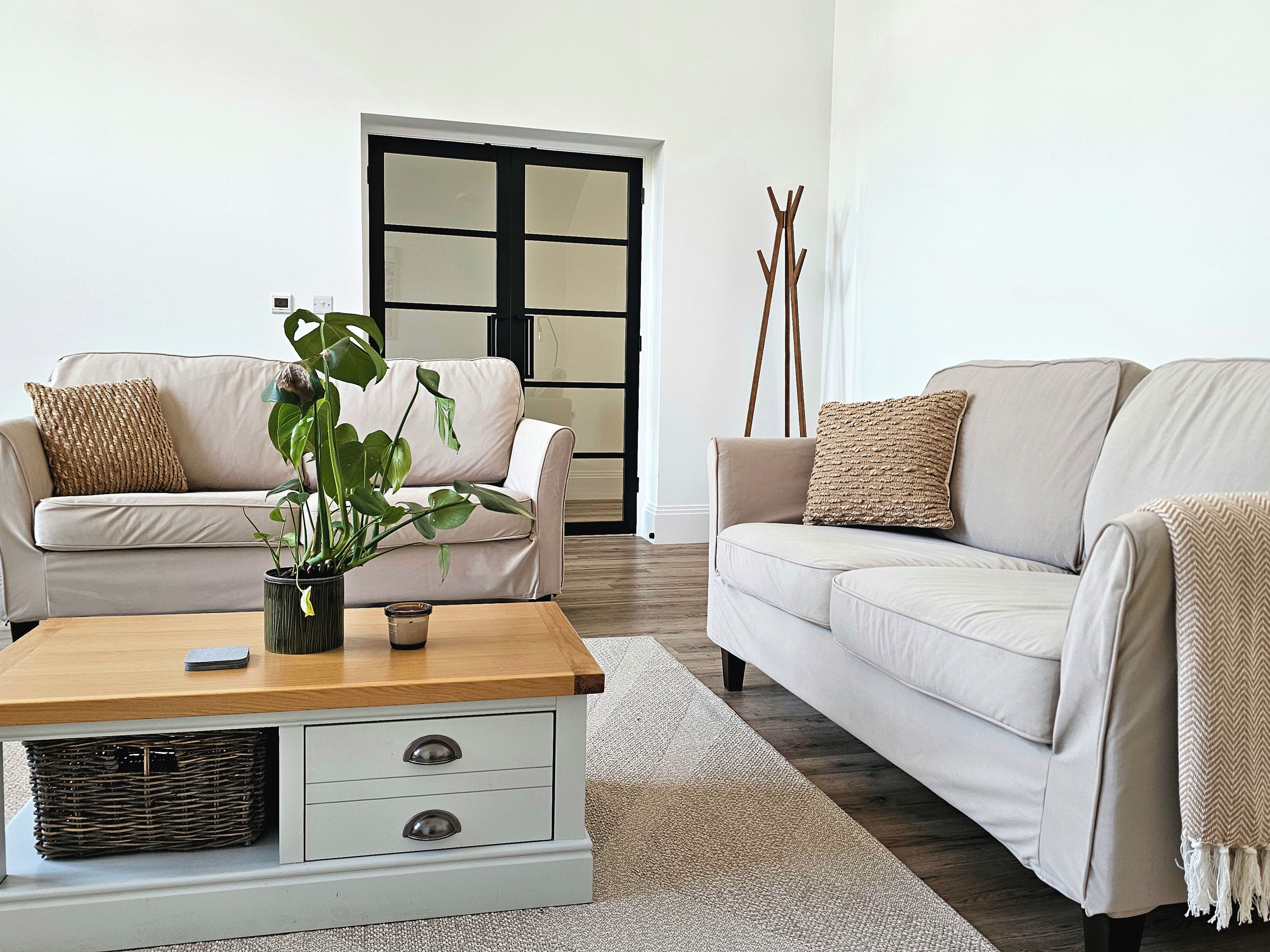 A living room with two sofas, a coffee table, a plant, and a wooden floor.