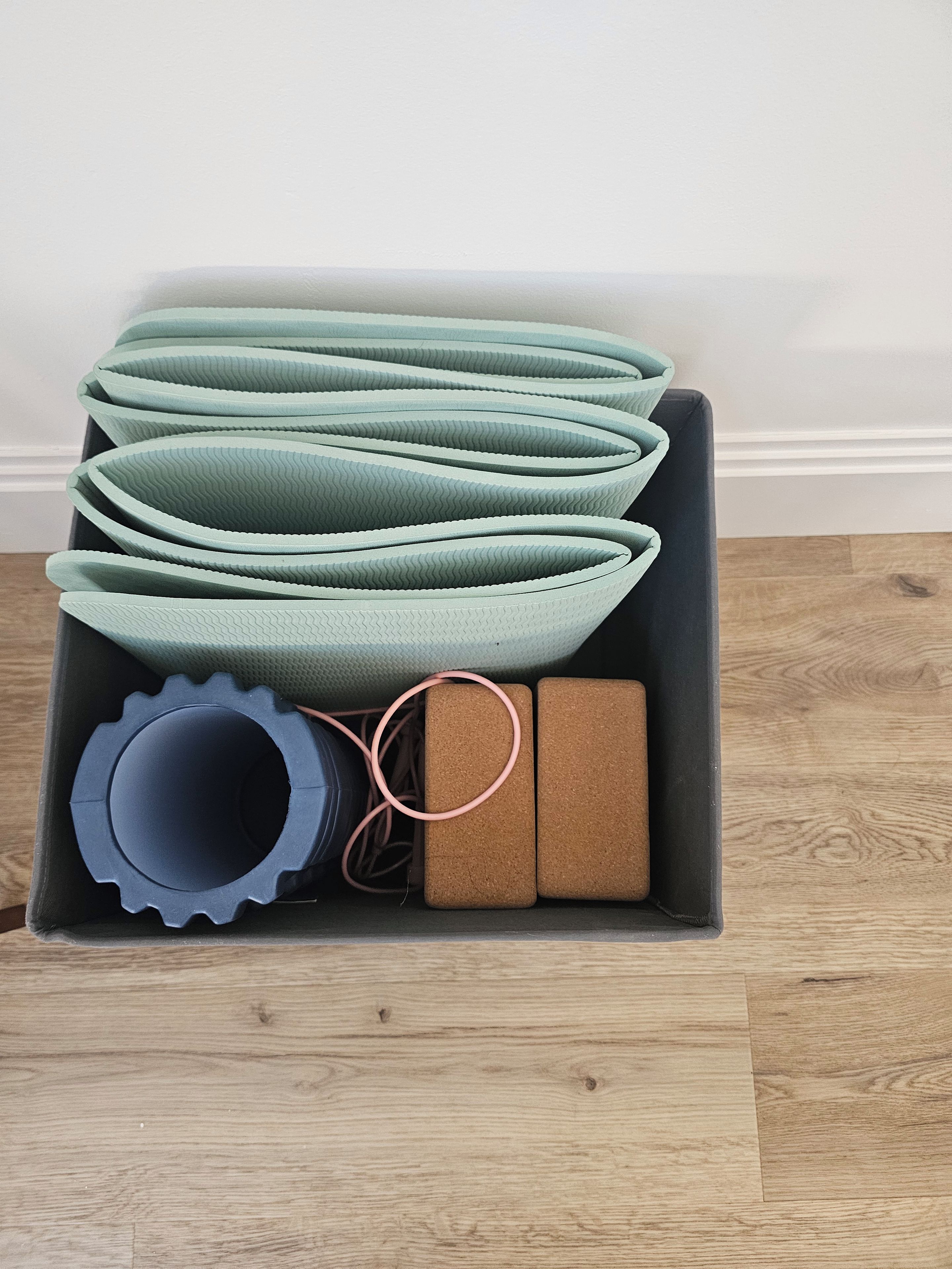 A storage box containing rolled-up mats, a blue cylindrical object, and two brown rectangular objects.