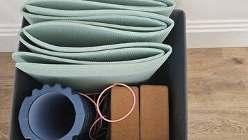A storage box containing rolled-up mats, a blue cylindrical object, and two brown rectangular objects.