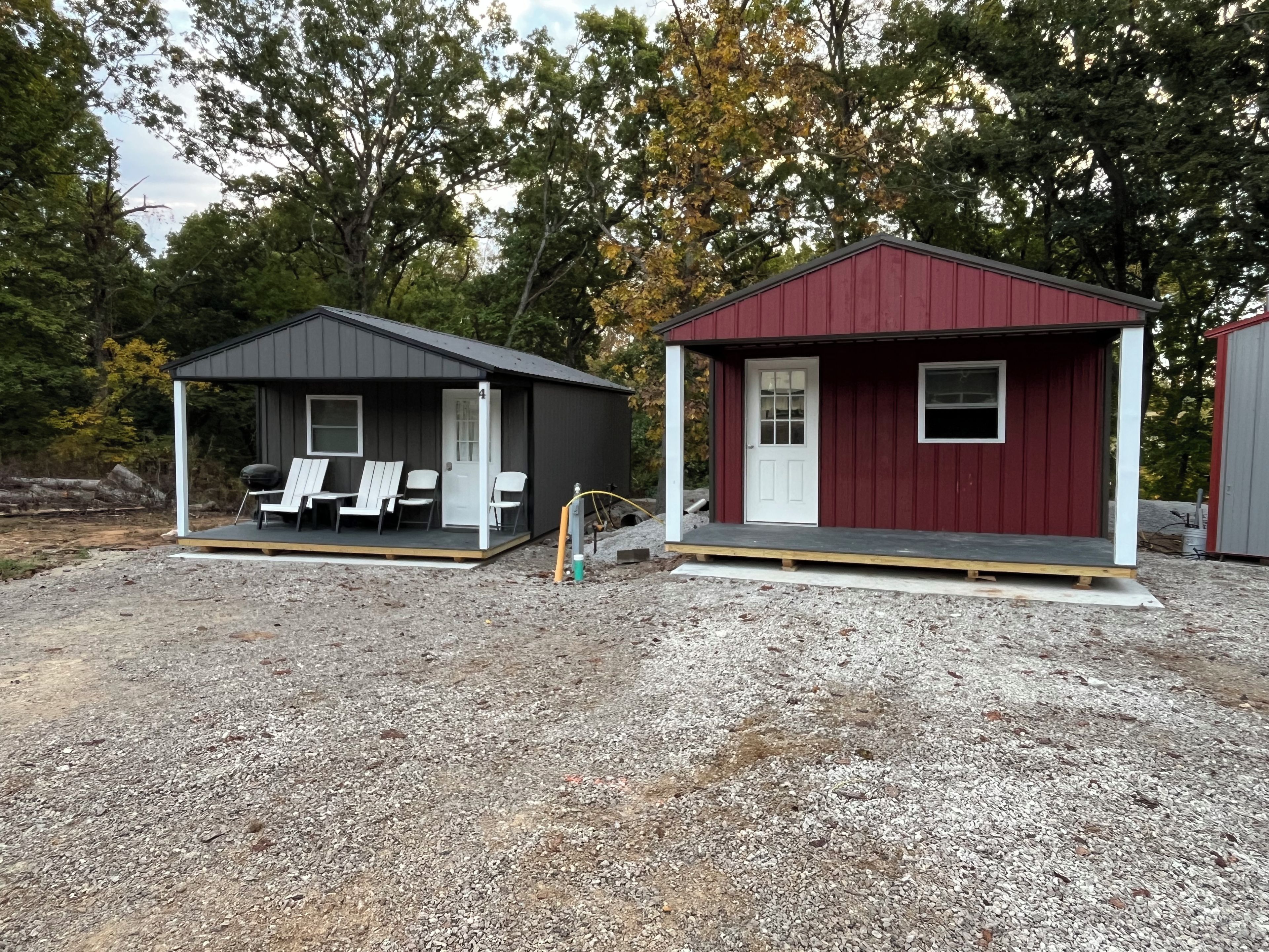 Deux petits chalets dotés d’un espace extérieur pour s’asseoir, l’un avec une véranda et l’autre avec une porte.