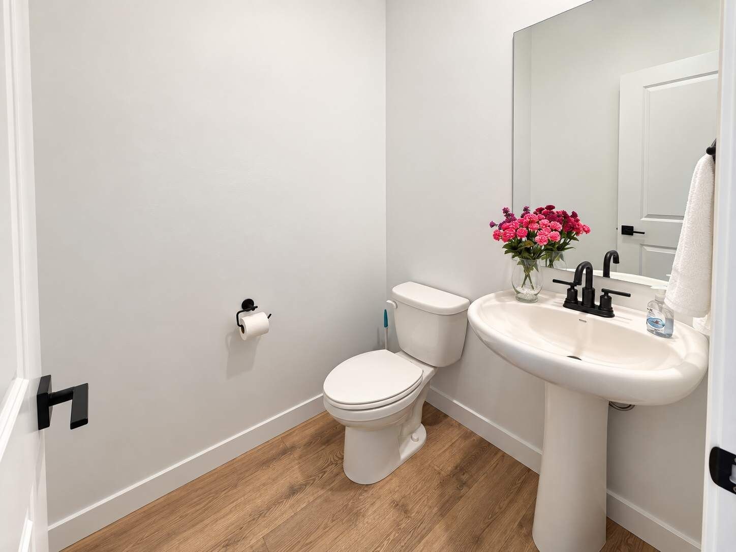 A bathroom with a toilet, sink, and mirror.