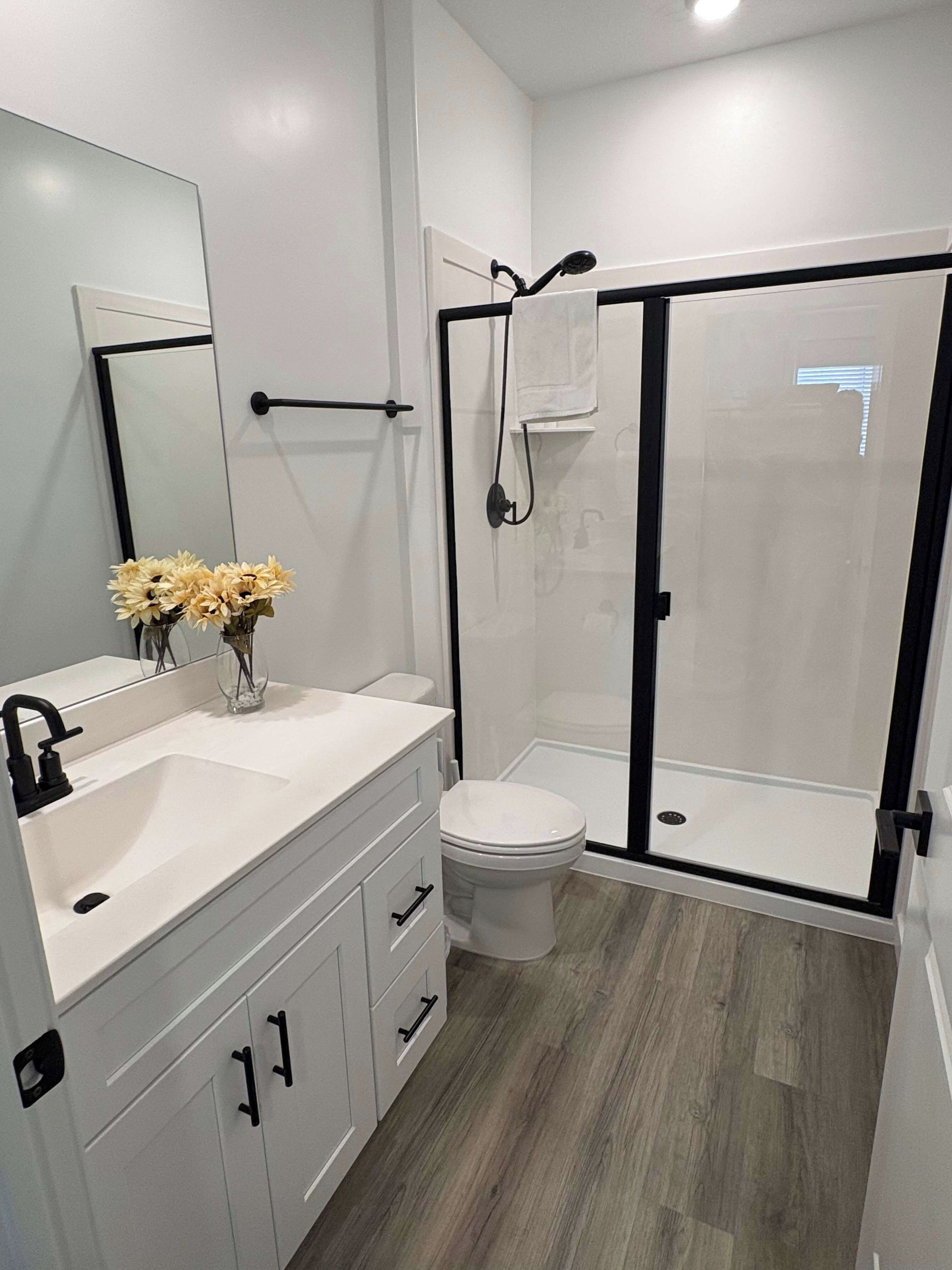 A modern bathroom with a white sink, a toilet, and a glass-enclosed shower.