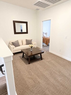 A room with a white sofa, a dark wooden coffee table, and a mirror on the wall. - Family Retreat - Sleeps 14 (Washington)