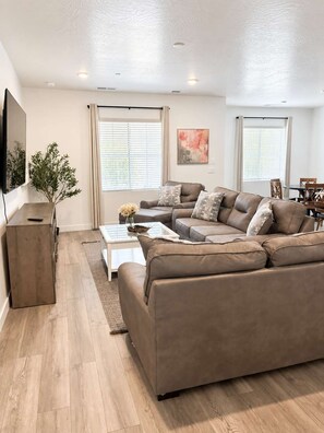 A modern living room with a sectional sofa, a coffee table, and a TV mounted on the wall. - Family Retreat - Sleeps 14 (Washington)