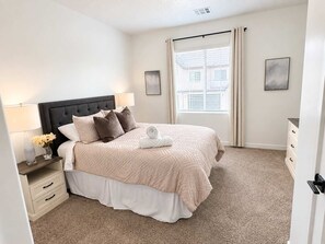 A bedroom with a bed, nightstands, a dresser, and a window with curtains. - Family Retreat - Sleeps 14 (Washington)