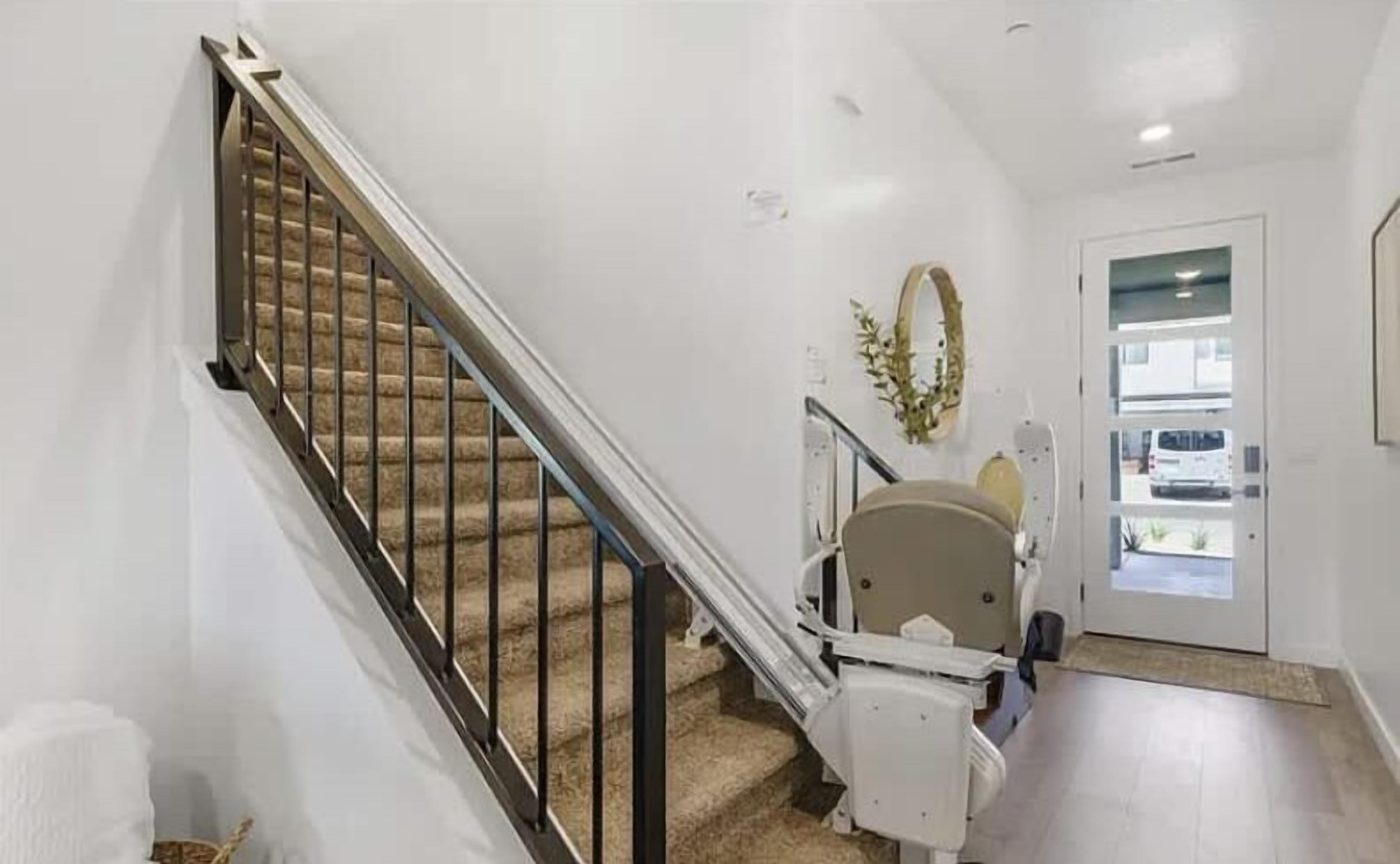 Un escalier avec une rampe, une porte ornée d’une guirlande et un mur blanc.